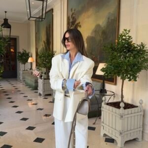 Femme portant le blazer crème Saint-Tropez Riviera en laine premium sur une chemise à rayures bleues.